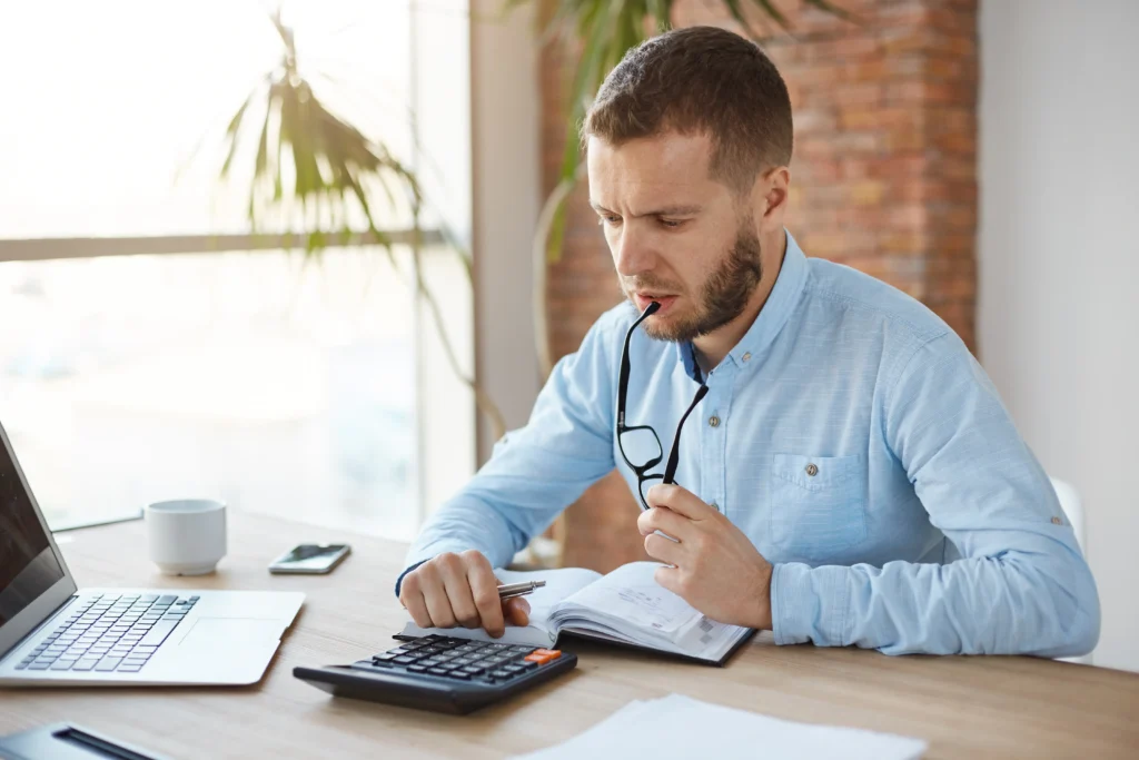 person reviewing financial documents worried tax documents pen calculator desk